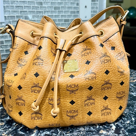 MCM Handbags - MCM Visetos Medium Drawstring 
Bucket Bag in Cognac. EUC